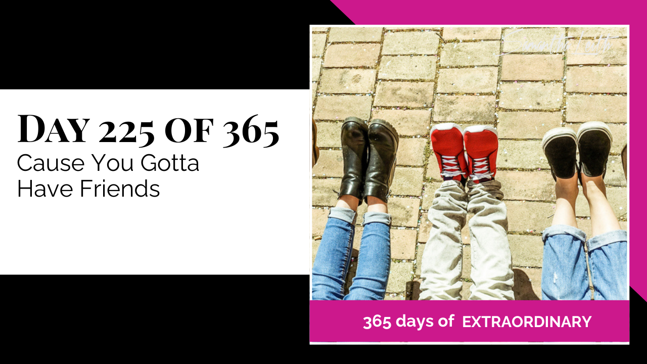 A photographic post featuring an aerial view of the lower legs and feet of three people sitting side-by-side, all wearing different shoes and casual bottoms, lying on a brick or stone patio. The person on the left wears black boots and cuffed blue jeans. The person in the center wears red Converse-style sneakers and light-colored pants. The person on the right wears black slip-on sneakers and cuffed blue jeans. The image is split with a title card on the left side that reads: "DAY 225 OF 365 Cause You Gotta Have Friends". Below the photo, a bright pink banner reads: "365 DAYS OF EXTRAORDINARY". A stylized signature in the top right corner says "Samantha Leith."