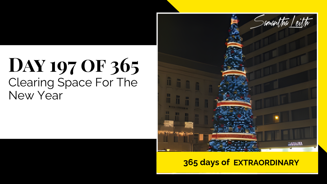 A nighttime photograph of a very tall Christmas tree adorned with blue lights and decorations in an urban setting, used to illustrate the concept of end-of-year review, decluttering, clearing mental and physical space, and preparing for New Year's goal setting.
