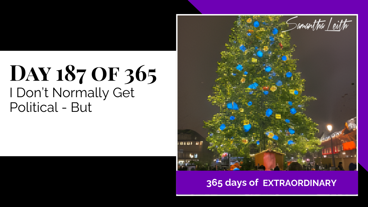 A nighttime photograph of a tall public Christmas tree decorated with saturated blue globe ornaments and lights, used as a visually striking, yet traditionally neutral, background to introduce an off-topic political discussion or social commentary on a blog.