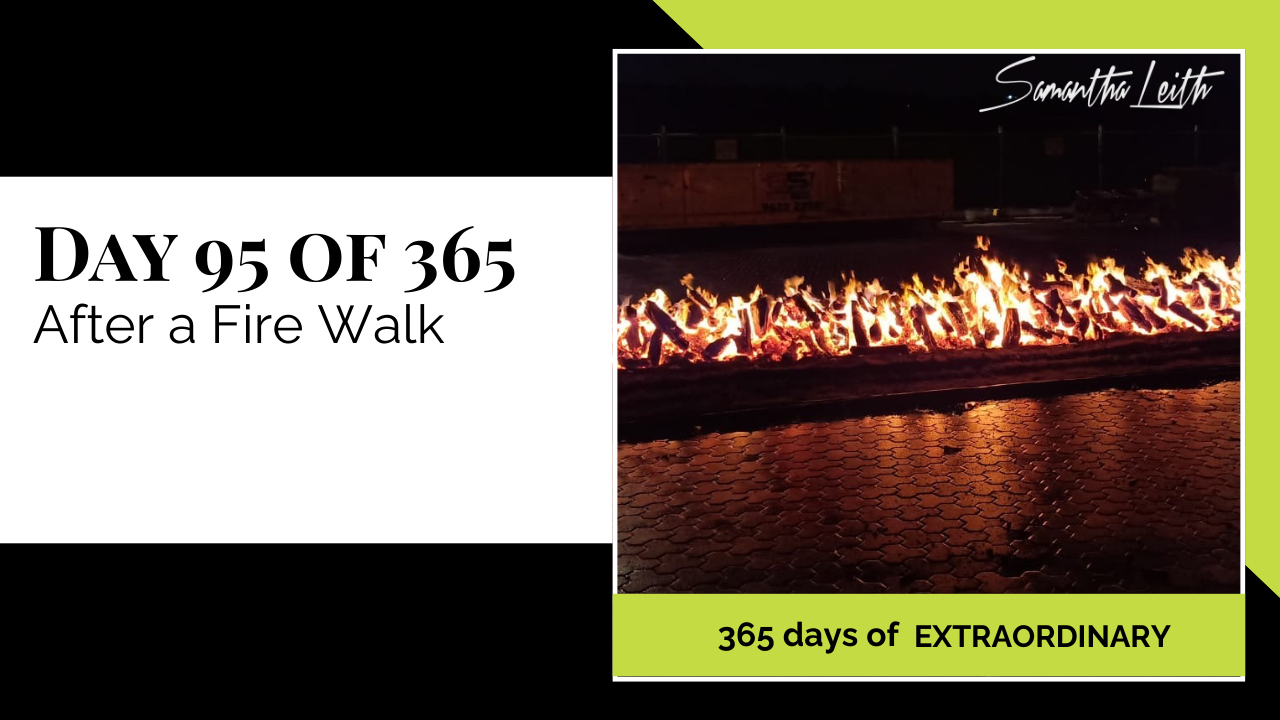 Blog image for Day 95 of Sam Leith's '365 Days of Extraordinary' series, showing a long, smoldering bed of glowing embers and logs on a dark paved surface after a firewalk event.