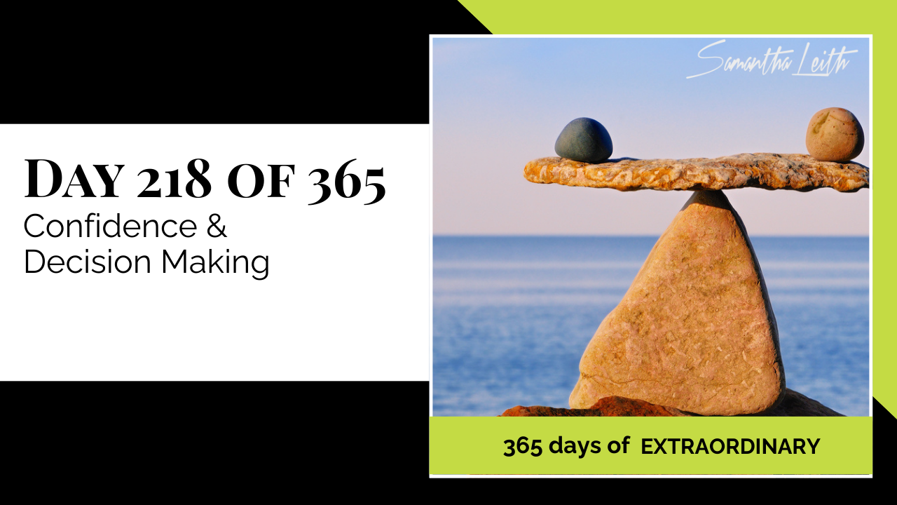 A photographic post featuring a perfectly balanced rock sculpture, or cairn, with a flat stone acting as a beam supported by a large, triangular stone, forming a natural scale. A small, dark gray stone rests on the left side of the beam, and a light brown, irregular stone rests on the right, maintaining balance. The sculpture is set against a blue sky and the ocean. The image is split with a title card on the left side that reads: "DAY 218 OF 365 Confidence & Decision Making". Below the photo, a lime green banner reads: "365 DAYS OF EXTRAORDINARY". A stylized signature in the top right corner says "Samantha Leith.