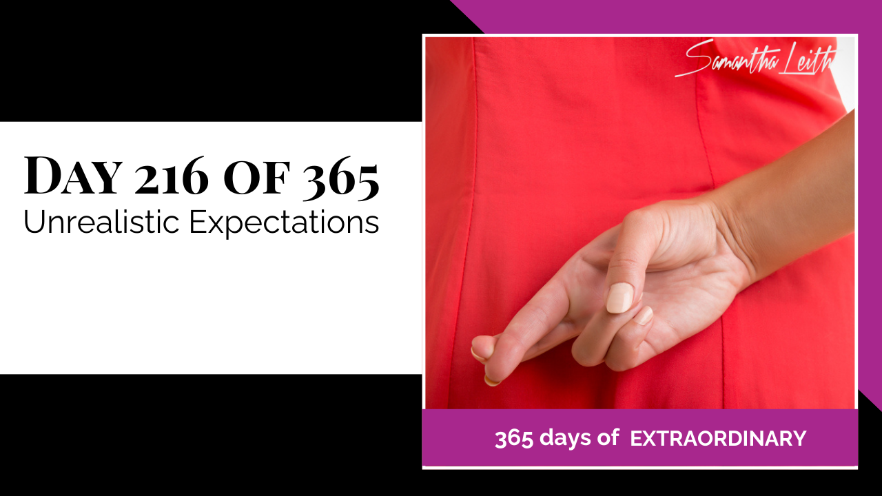 A photographic post featuring a close-up image of a person's hand positioned behind their back, with their index and middle fingers crossed, a gesture traditionally used to signal a lie or insincerity. The person is wearing a bright red dress or garment. The image is split with a title card on the left side that reads: "DAY 216 OF 365 Unrealistic Expectations". Below the photo, a magenta banner reads: "365 DAYS OF EXTRAORDINARY". A stylized signature in the top right corner says "Samantha Leith.