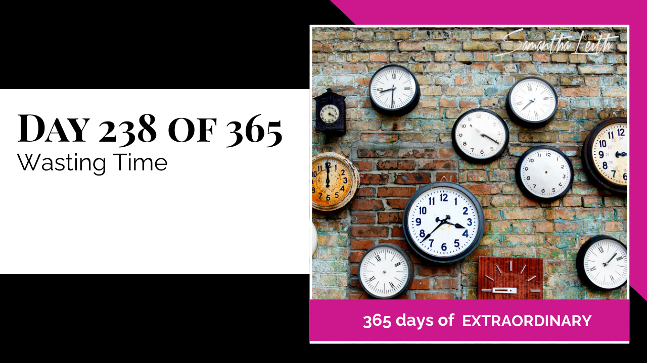 Graphic for the "365 days of extraordinary" series by Samantha Leith. The text reads "DAY 238 OF 365 Wasting Time." The visual is a collection of various-sized wall clocks and an old clock hanging on a distressed red brick wall.