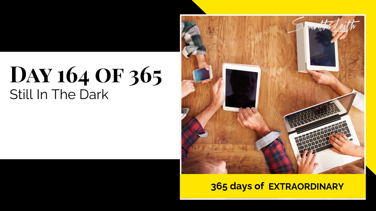 High-angle photograph of several people's hands using digital devices (laptops and tablets) on a wooden desk, with the screens remaining black, representing a business or group struggling with a lack of information, transparency, or knowledge on a key issue.