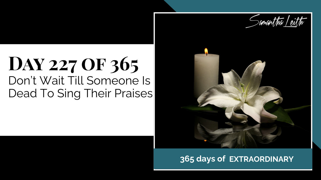 A photographic post featuring a still life of a single white lily and a tall, lit white candle set against a dark background, reflecting on the surface. The image is split with a title card on the left side that reads: "DAY 227 OF 365 Don't Wait Till Someone Is Dead To Sing Their Praises". Below the photo, a dark teal banner reads: "365 DAYS OF EXTRAORDINARY". A stylized signature in the top right corner says "Samantha Leith."
