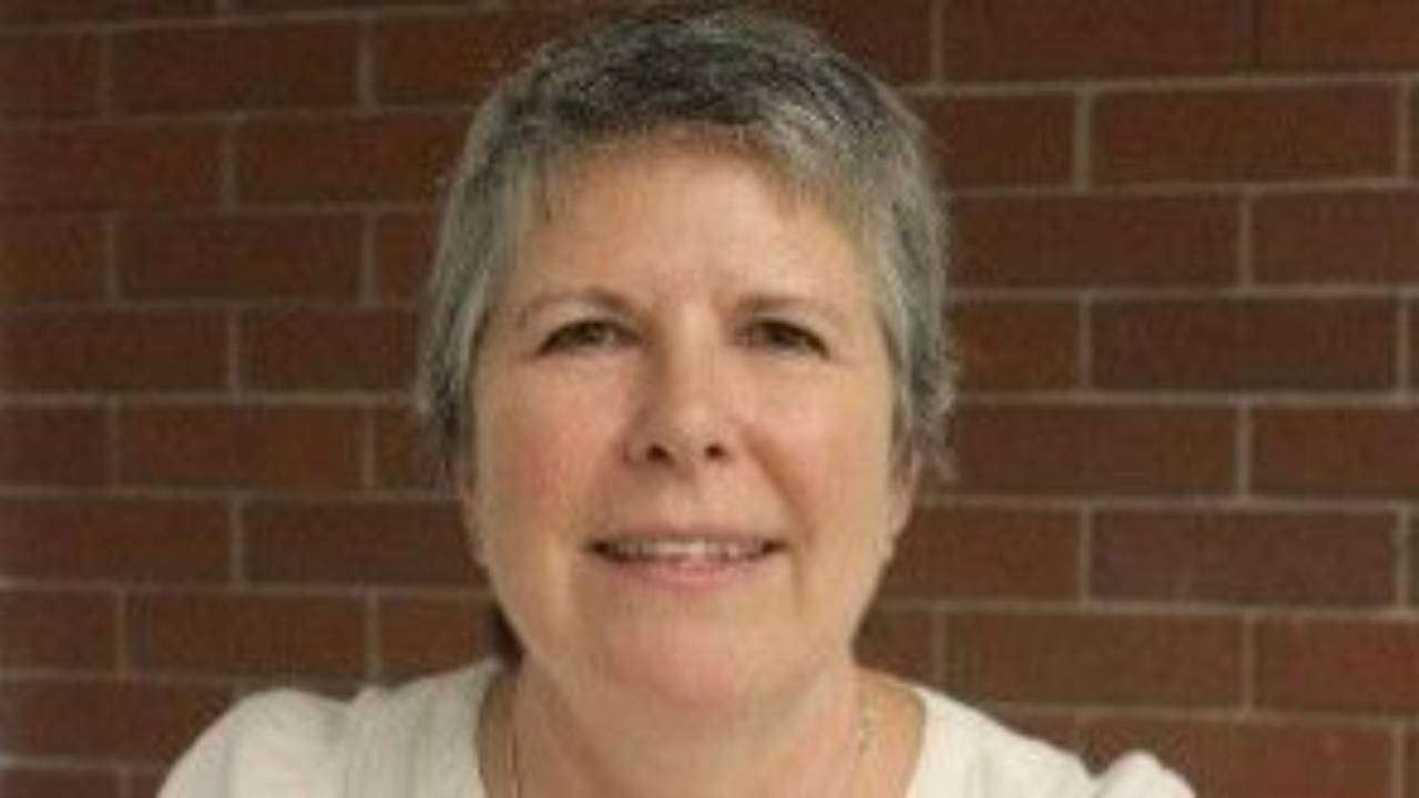 Ruth Duggan, Occupational Therapist, seated at a desk and smiling warmly in a softly lit professional portrait. The image conveys reflection, approachability, and professionalism.
