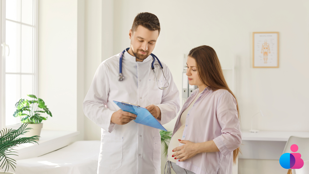 Pregnant woman stands beside doctor who is showing her the clipboard he is looking at.