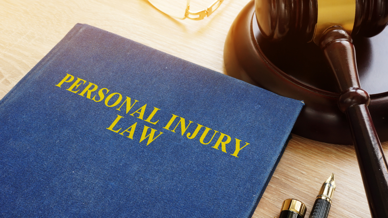 A close-up of a legal book labeled “Personal Injury Law” next to a judge’s gavel, representing legal risk and liability for businesses.