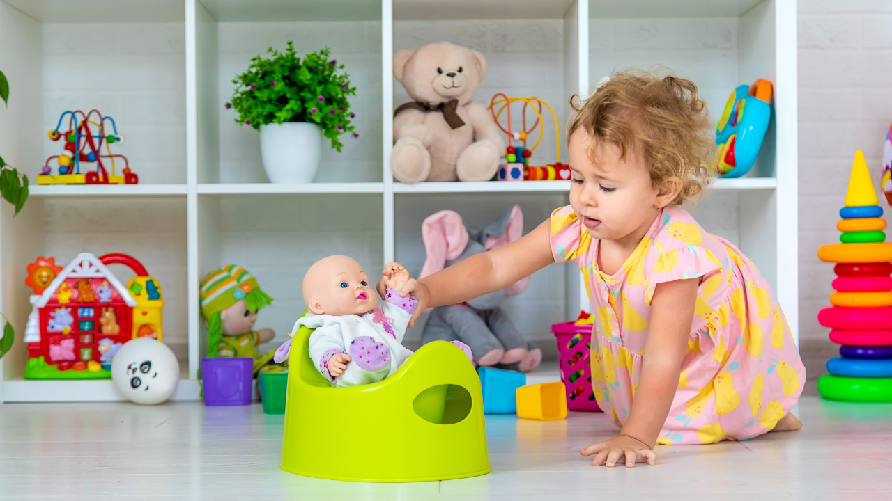 toddler puts their baby doll on the potty
