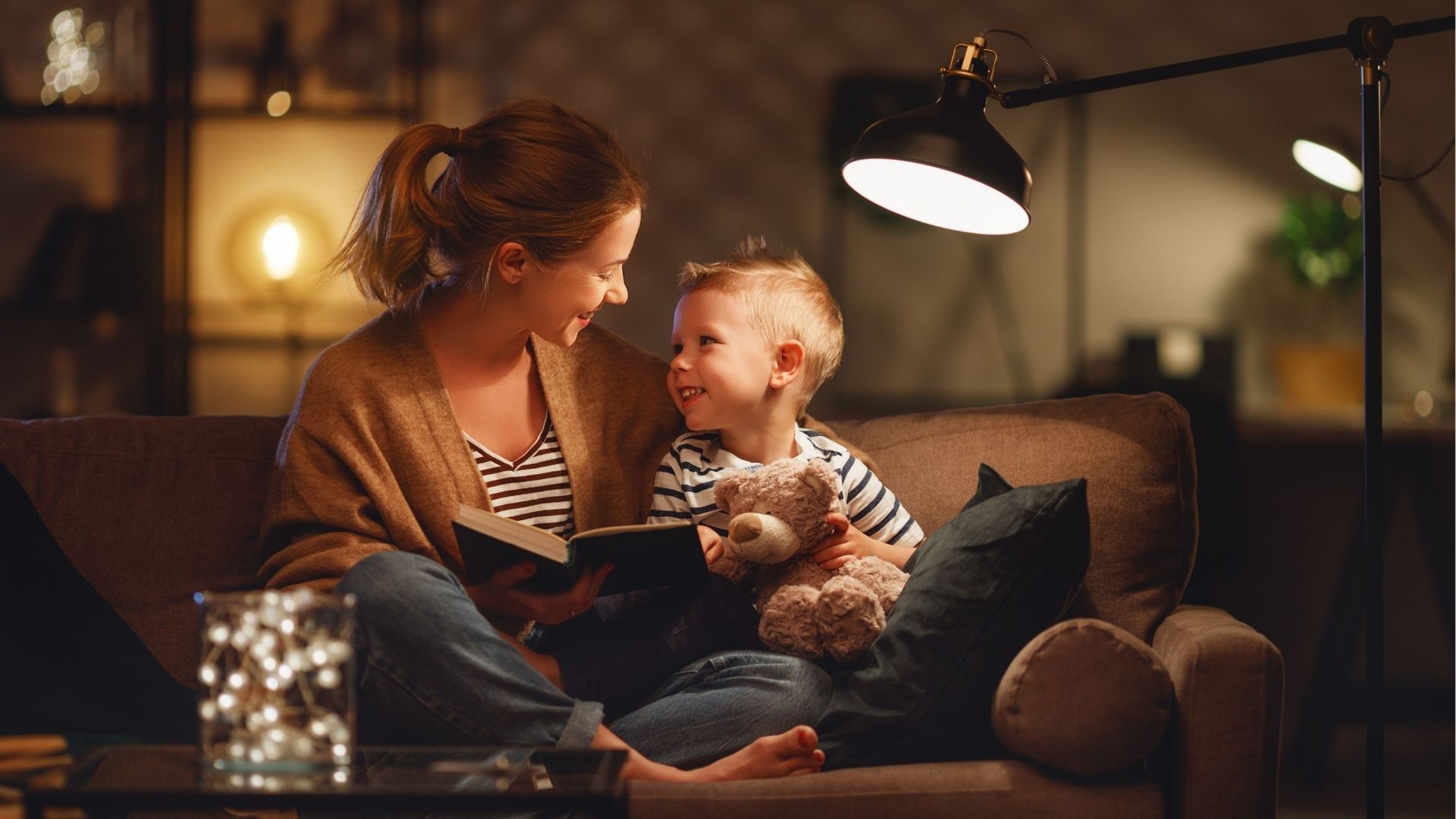 Maman lit une histoire du soir à son jeune garçon sur le canapé, moment de connexion parent-enfant