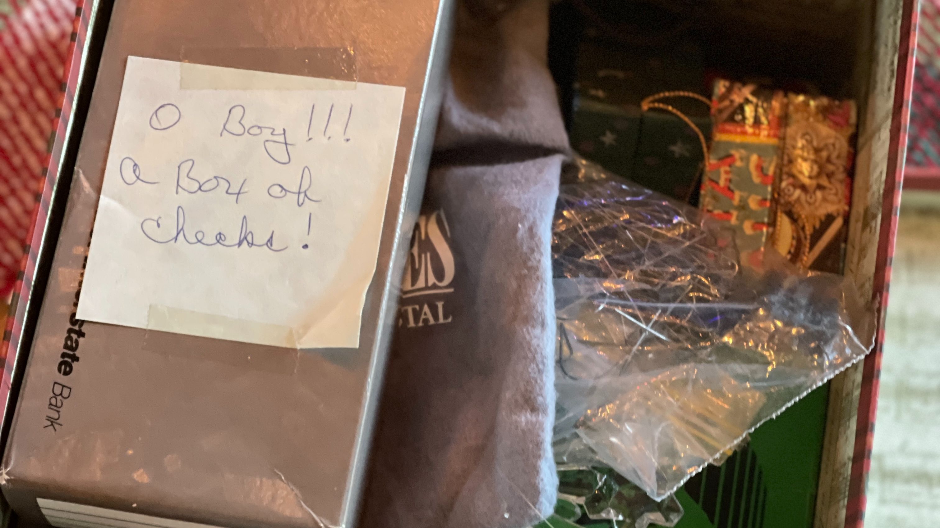 Old holiday check box used as a gift, with a post-it note joking ‘O’Boy!! A box of checks!’ representing holiday spending humor.