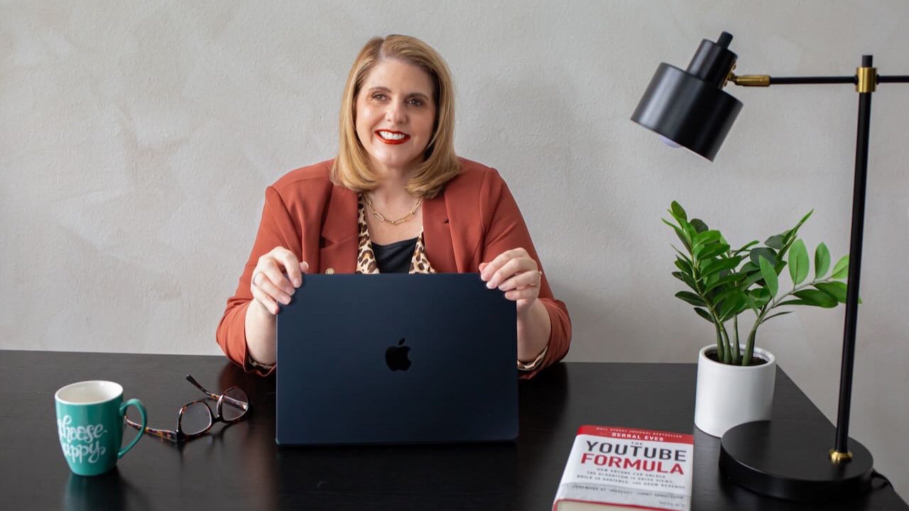 Kathy Sizemore, YouTube strategist for coaches, at her desk with The YouTube Formula book