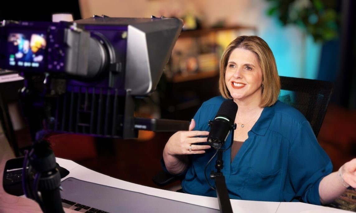 Business owner starting a YouTube channel, filming a video at her desk with a simple camera setup