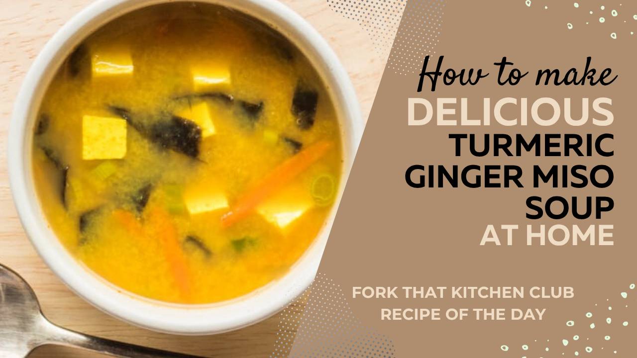 White bowl of turmeric ginger miso soup with cubes of tofu, grated carrots, green onions, and nori in golden broth 