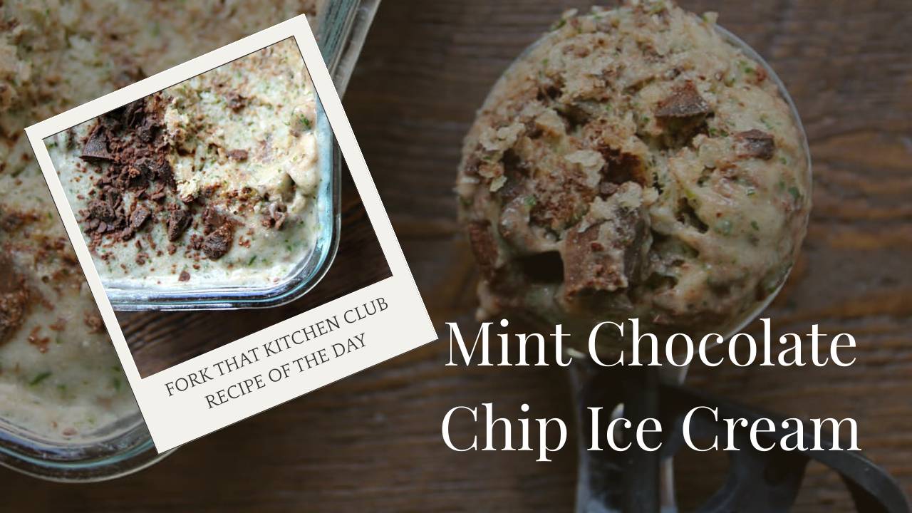 Scoop of mint chocolate chip ice cream in an ice cream scoop next to a glass tray of ice cream on a dark woden surface