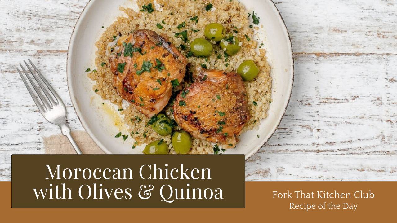 Moroccan chicken thighs with golden-brown skin on bed of quinoa with green olives on white plate with gold rim, fork on left side, light wooden table surface