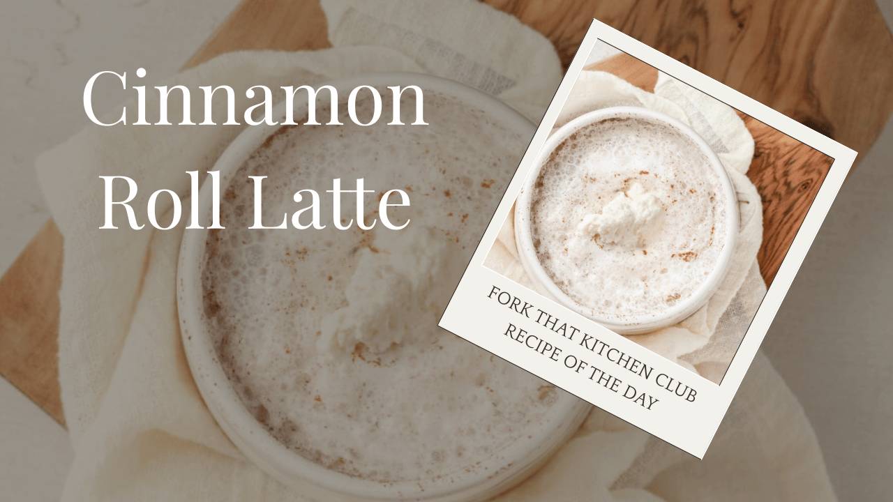 Overhead view of a white mug of cinnamon roll latte topped with whipped cream and cinnamon sitting on a cream linen napkin