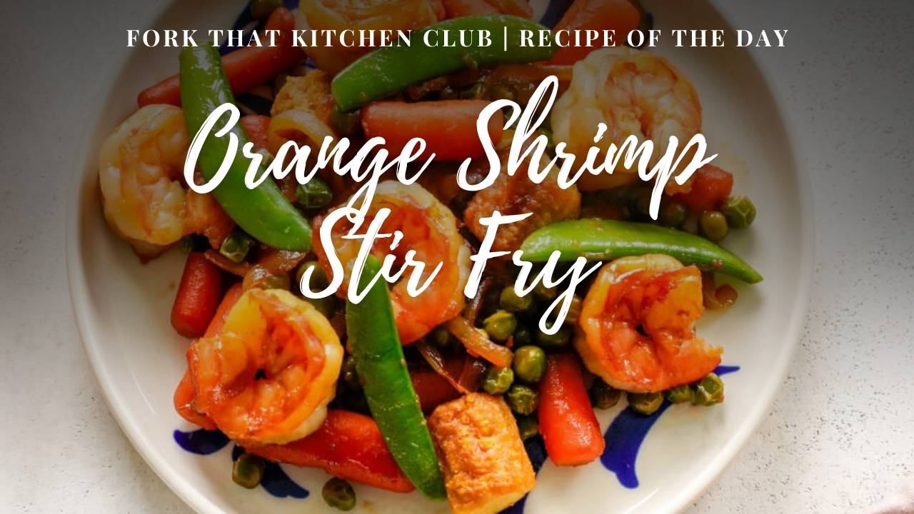 Orange shrimp stir fry with snap peas, carrots, and baby corn on a white & blue plate on light surface