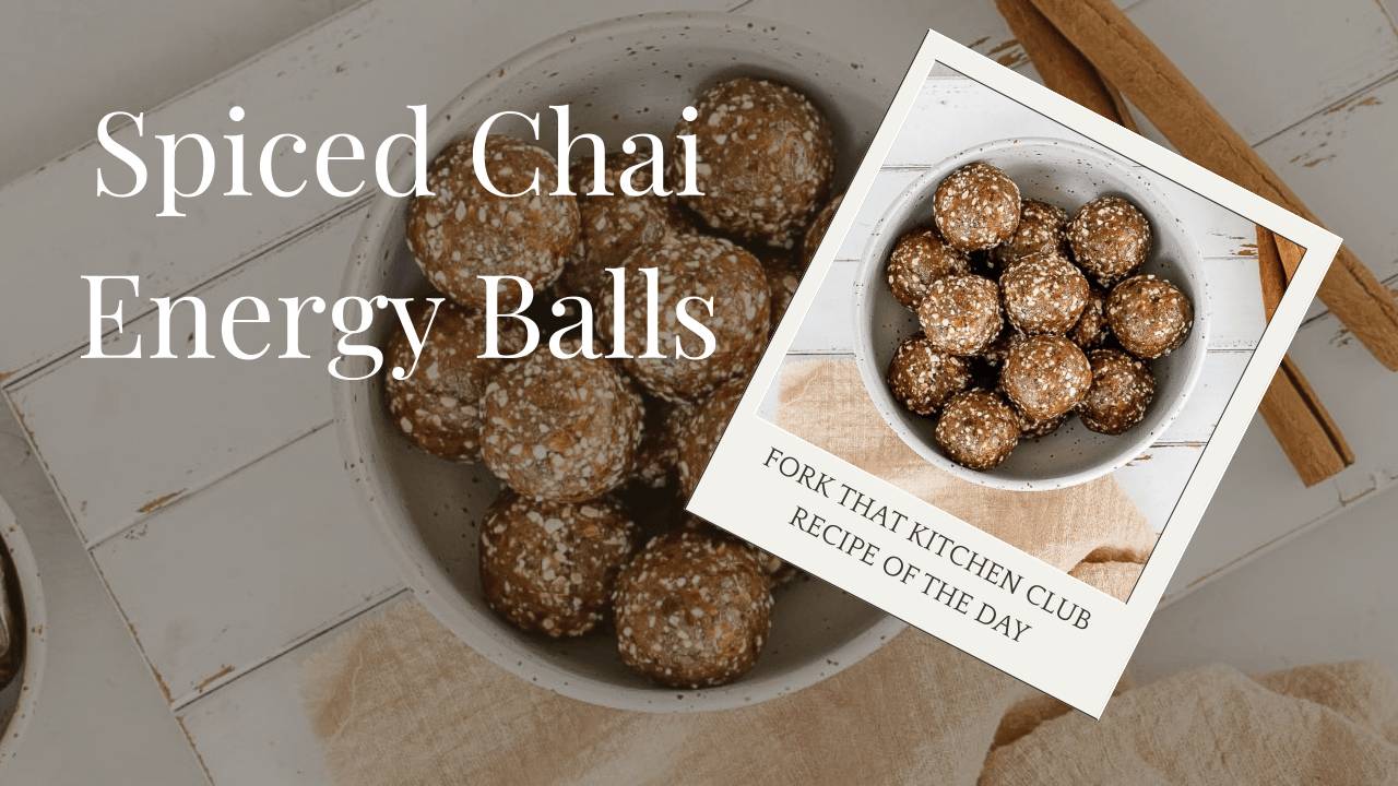 Spiced chai energy balls arranged in white bowl on a white, distressed painted, wood surface with cinnamon sticks to the right and a small bowl of dates to the left with a beige linen napkin partially visible near the bottom of the bowl