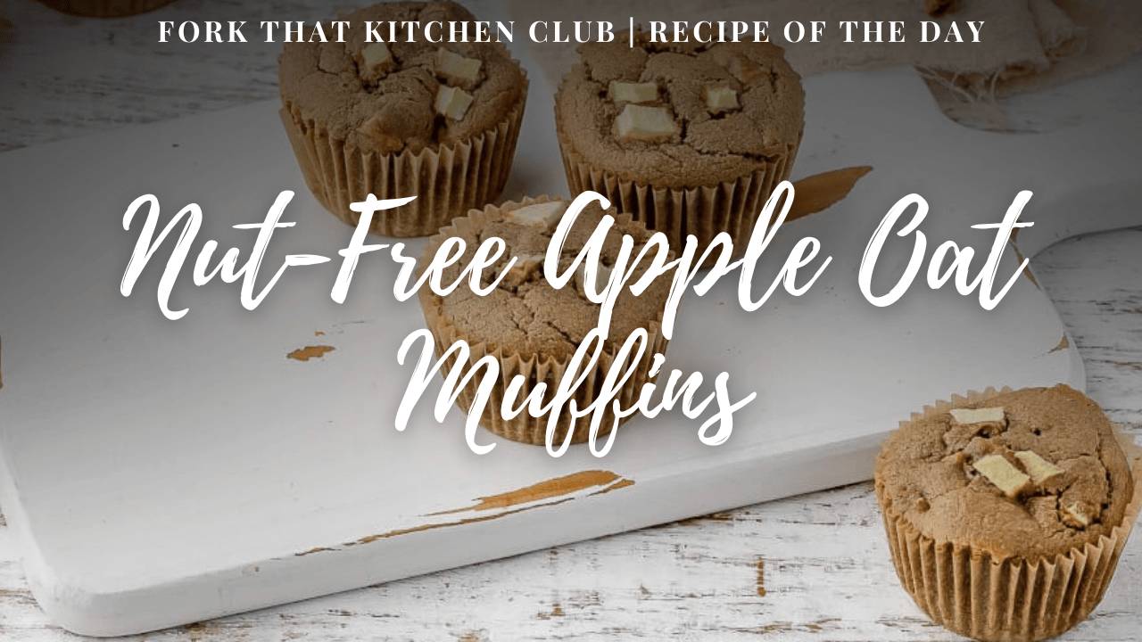 Nut-free apple oat muffins topped with diced apple pieces in brown paper liners on white serving board and one muffin in the foreground