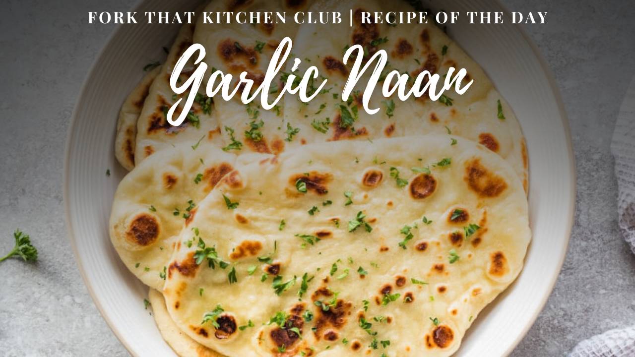 Stack of golden garlic naan with charred bubbles and parsley garnish on round white plate