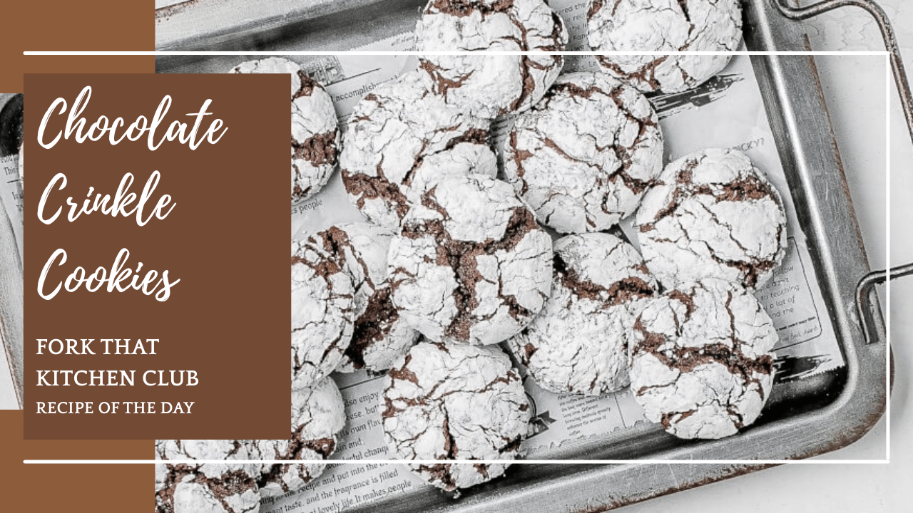 Chocolate crinkle cookies with powdered sugar coating on metal baking sheet lined with parchment paper, dark chocolate showing through crackled white surface, multiple cookies arranged haphazzardly with some stacked on top of each other