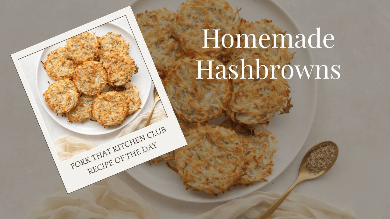 White plate with round, golden-brown hashbrowns arranged in casual pile showing crispy edges with cream-colored linen napkin in corner & brass spoon resting beside plate