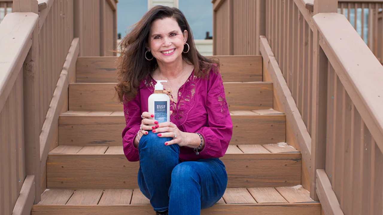 A woman seated on outdoor steps, smiling and holding a skincare product featured in the blog about increasing Shopify sales.