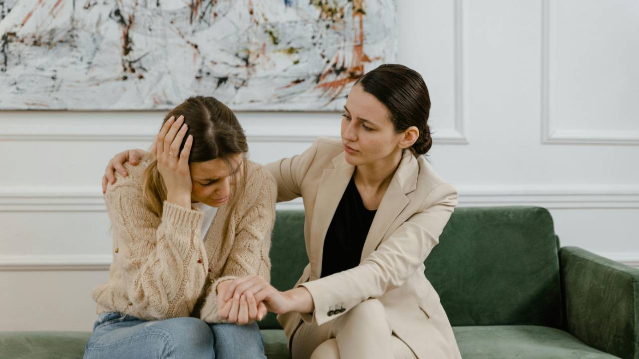 A compassionate woman comforting another who is upset, symbolizing the fine line between helping with empathy and rescuing from obligation.