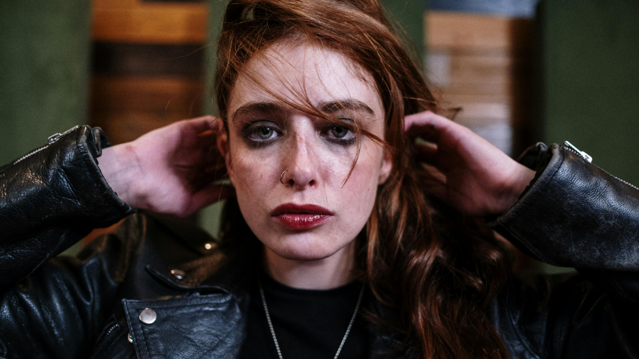 Woman with a steady, introspective gaze wearing a black leather jacket, symbolizing inner strength, self-respect, and the daily self-worth practice of reclaiming personal power.
