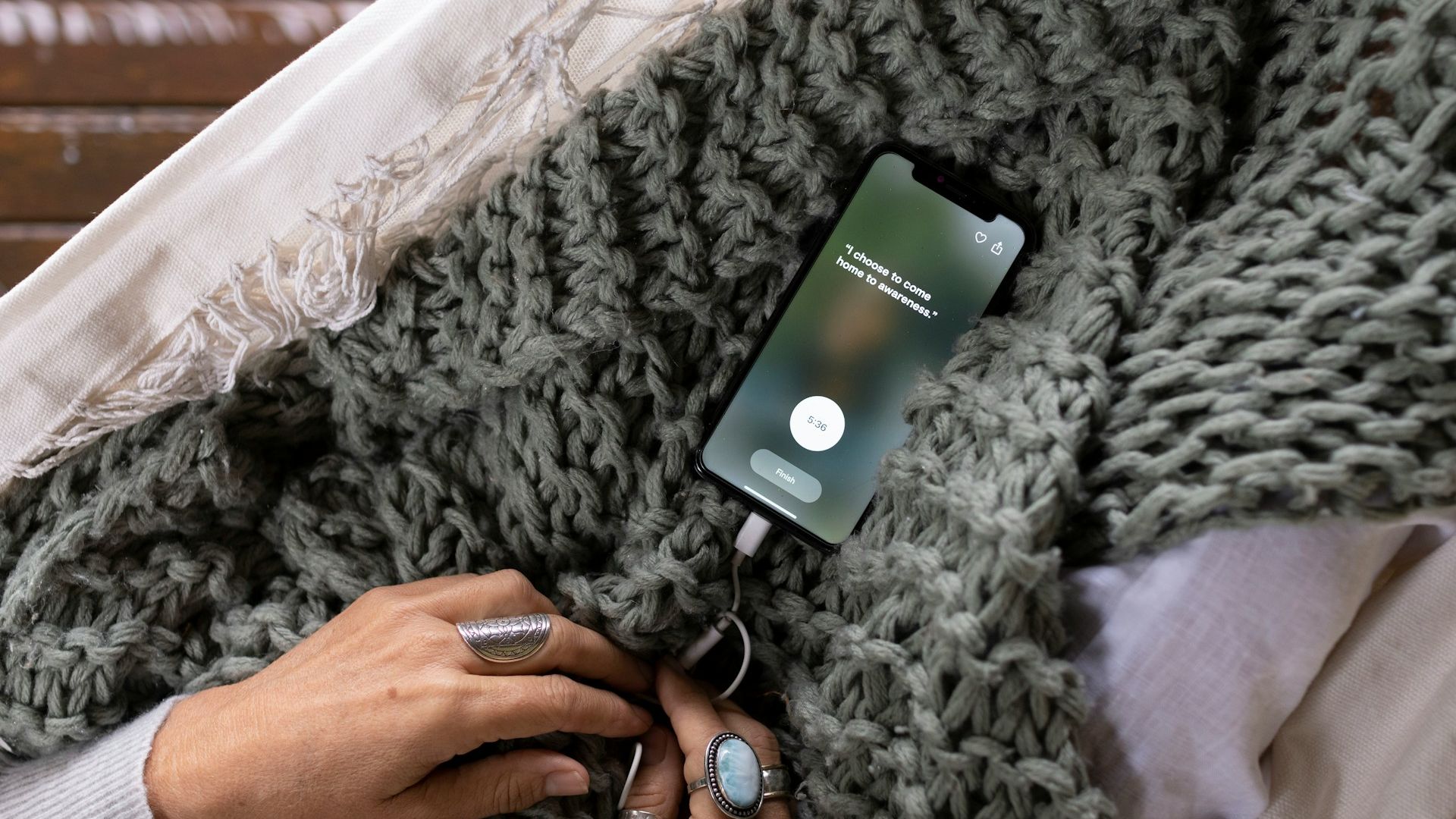 Image shows a phone with a meditation quote on top of a blanket