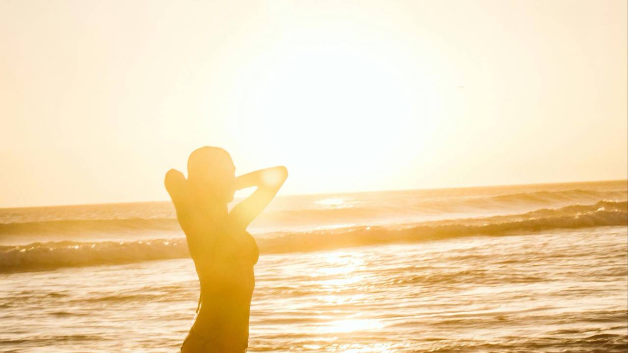 Silhouette of a woman walking toward bright, warm light along an open path, symbolizing stepping into a new timeline, intuitive expansion, and the energetic shift into a higher version of yourself.