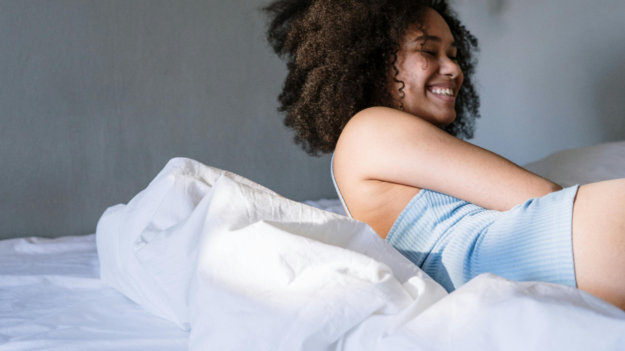 Woman resting peacefully in morning light, symbolizing rest, clarity, and alignment with personal energy cycles.