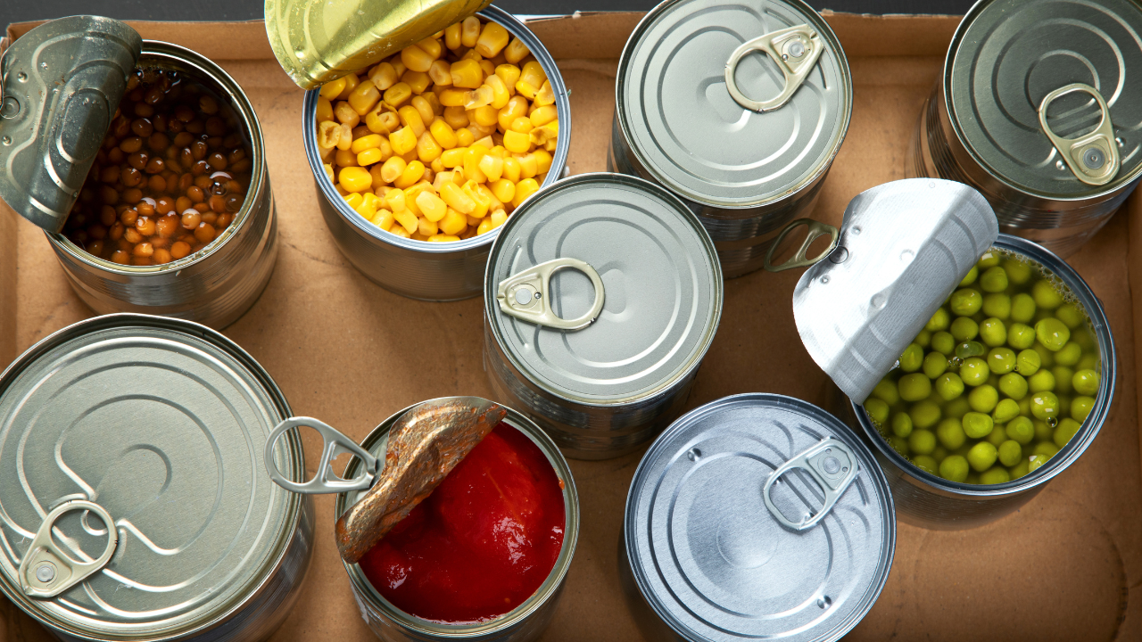 a variety of canned foods, opened, displaying the food inside such as peas, and corn