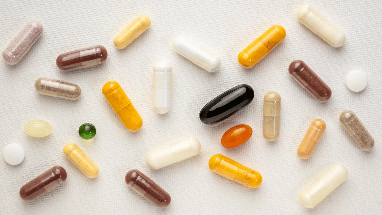 a variety of different supplement pills and capsules of different colors against a white background