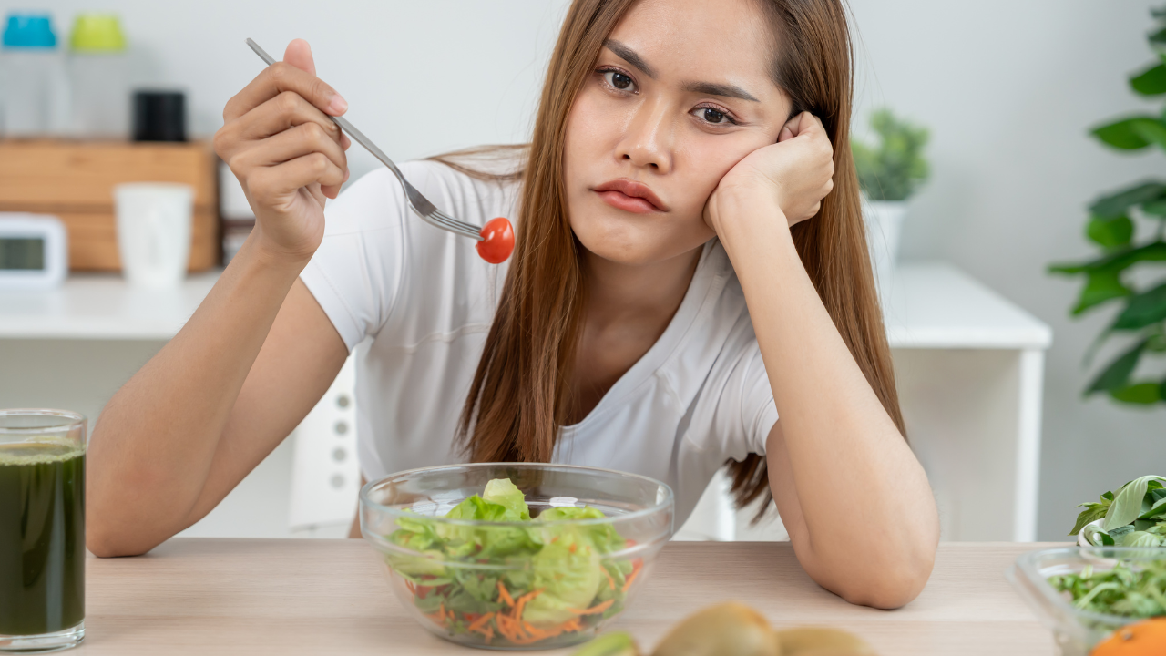 a woman holding a fork with a tomato on it looking upset about her bland salad
