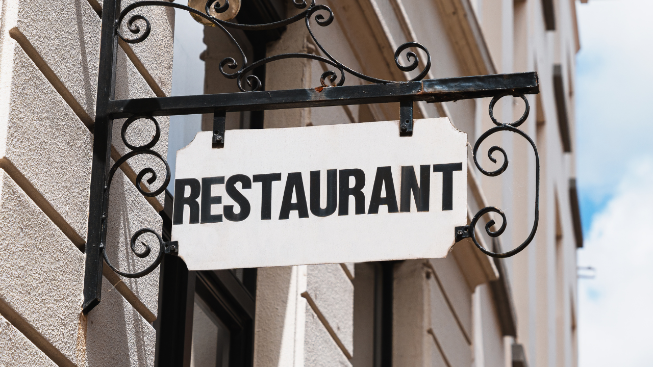 A fancy sign on the side of a concrete wall that says "restaurant"