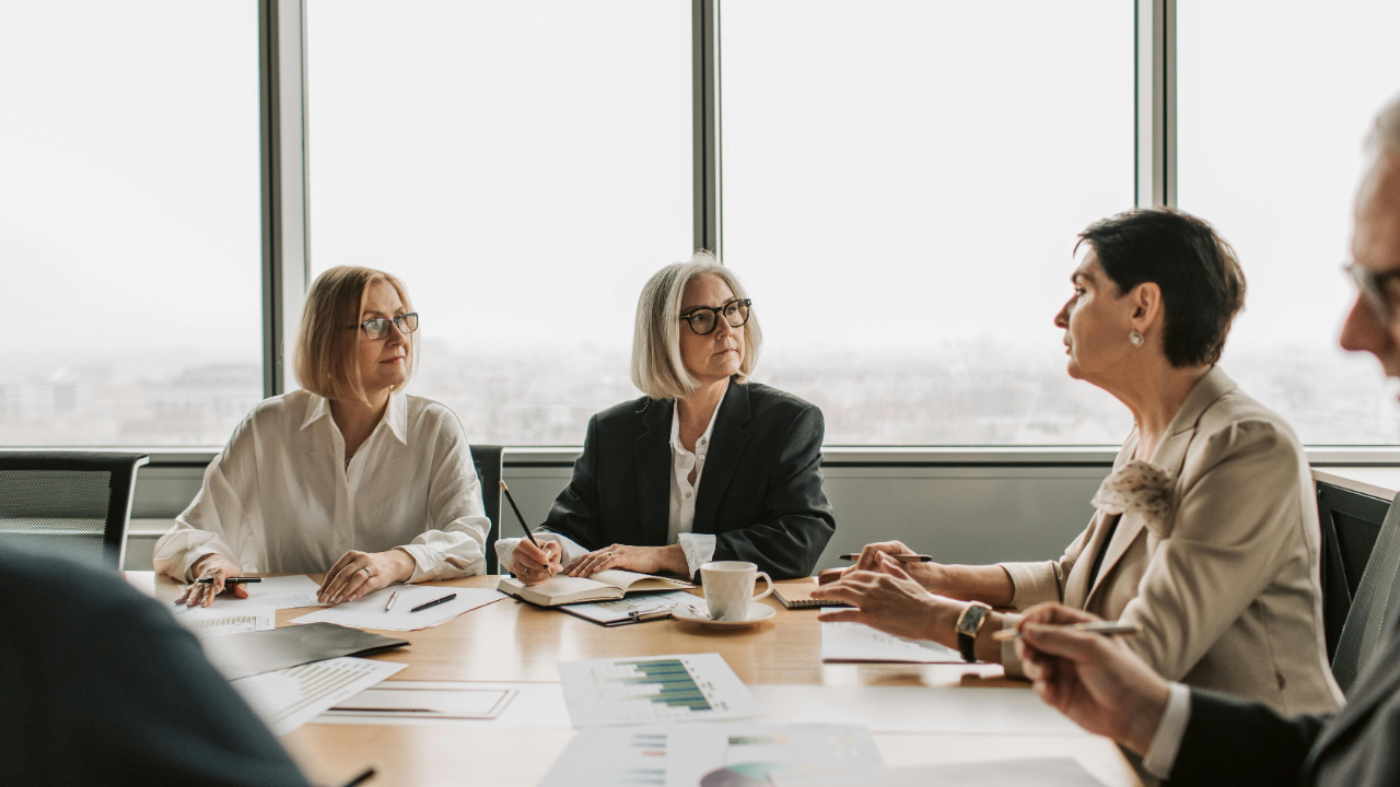 a group of people, a woman speaking while others are listening intently, cloudy cityscape behind
