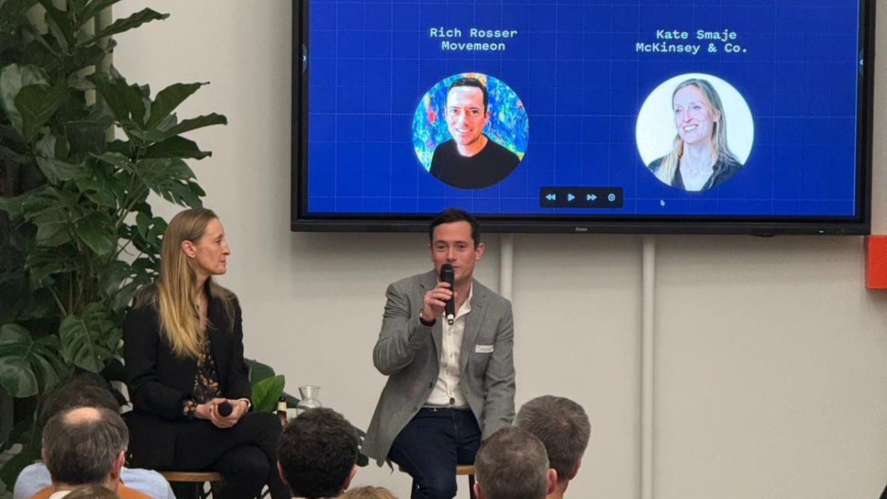two speakers, male and female, in front of a room full of guests