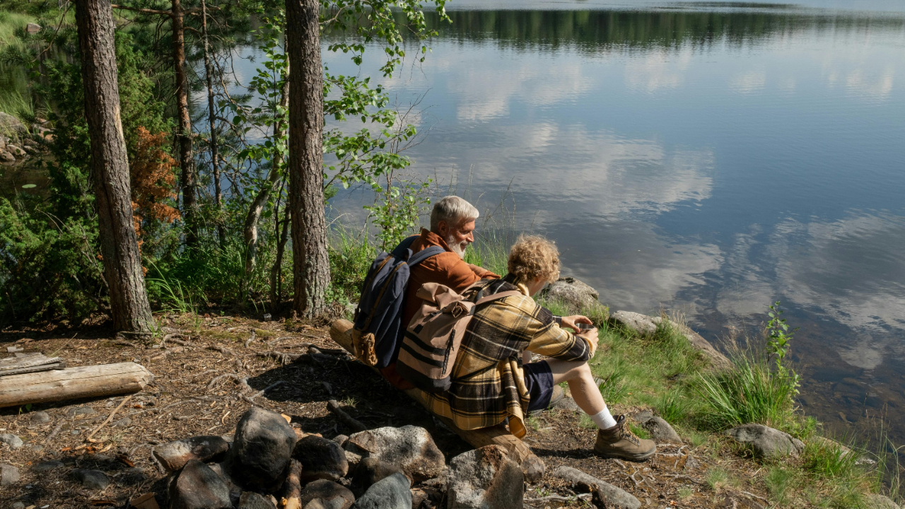 Two people sitting beside a calm lake, reflecting on success and personal growth.