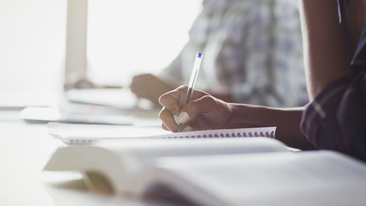 Person writing in a notebook during professional coach training, representing positive psychology coaching education and evidence-based practice