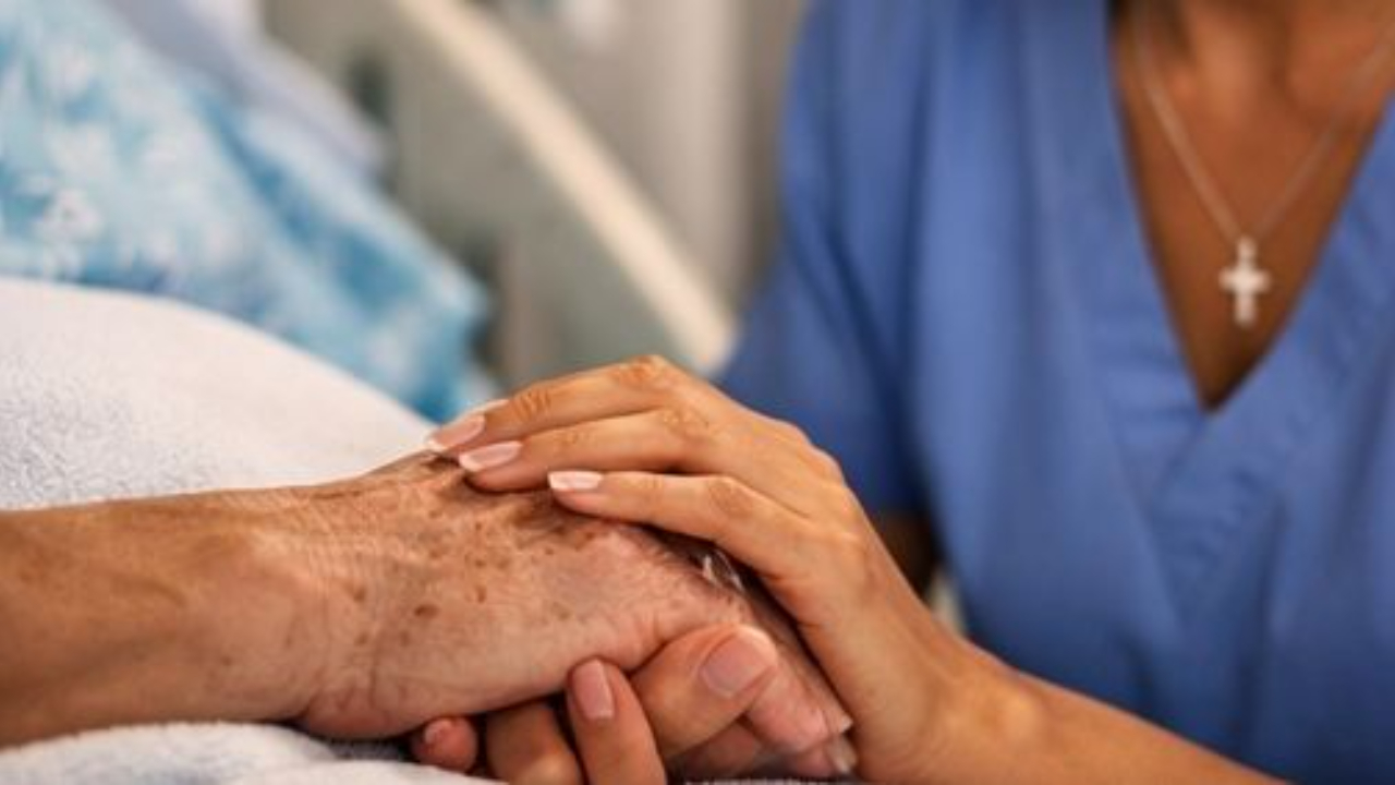 Nurse holding patient's hand representing faith and compassionate nursing care