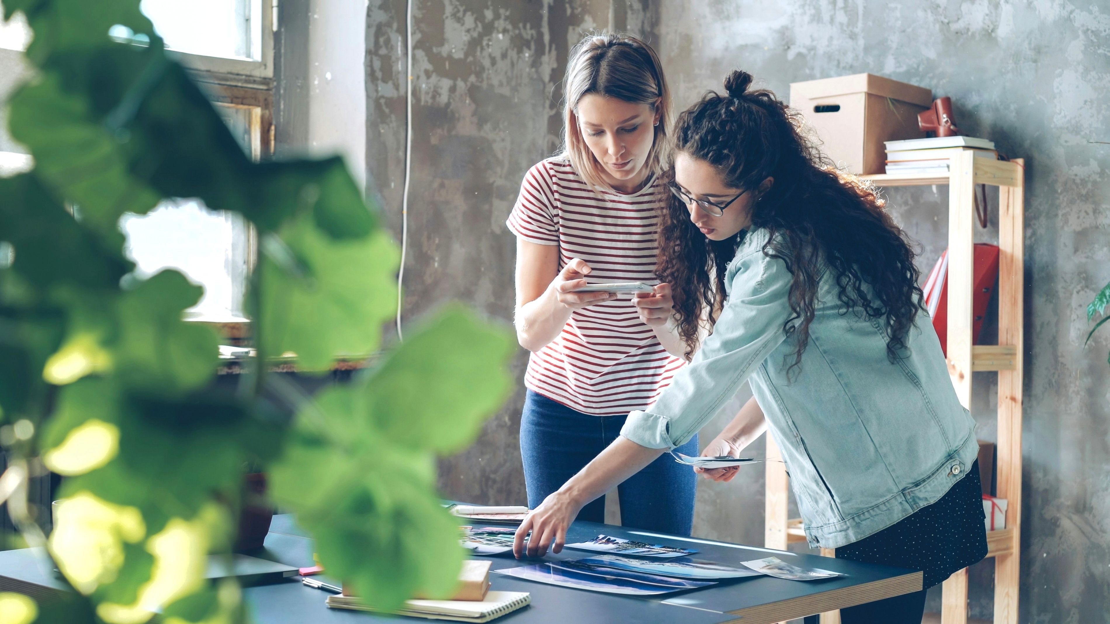 2 women looking through photos on a desk