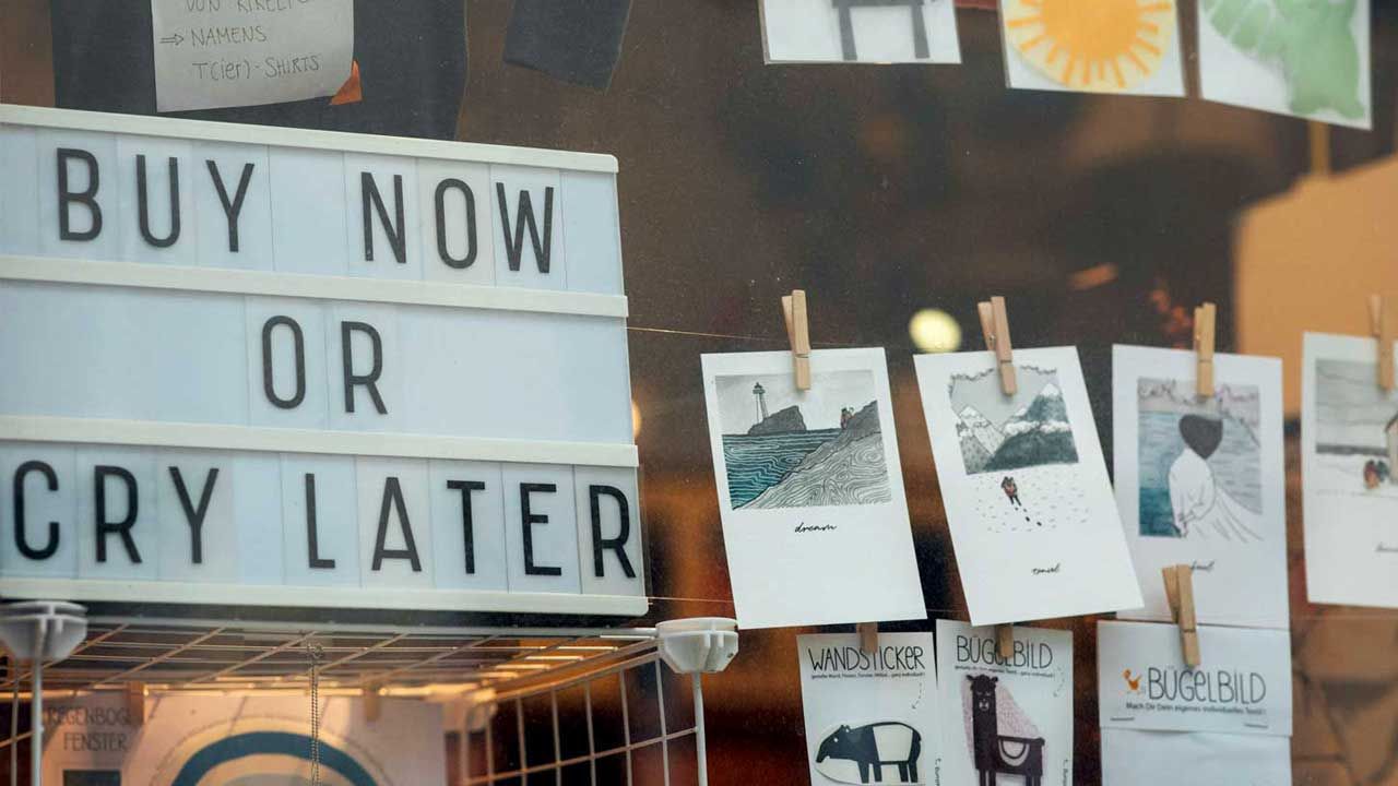 shop window with a sign that says, "Buy now or cry later."