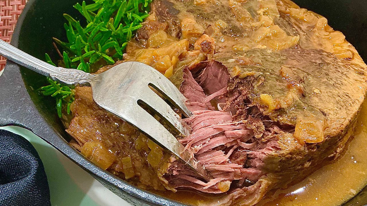 Old-fashioned Cajun chuck roast with onion gravy in a cast iron pot.