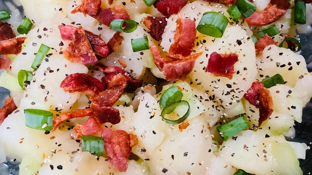 Hot German potato salad with bacon, red onion, and fresh herbs.