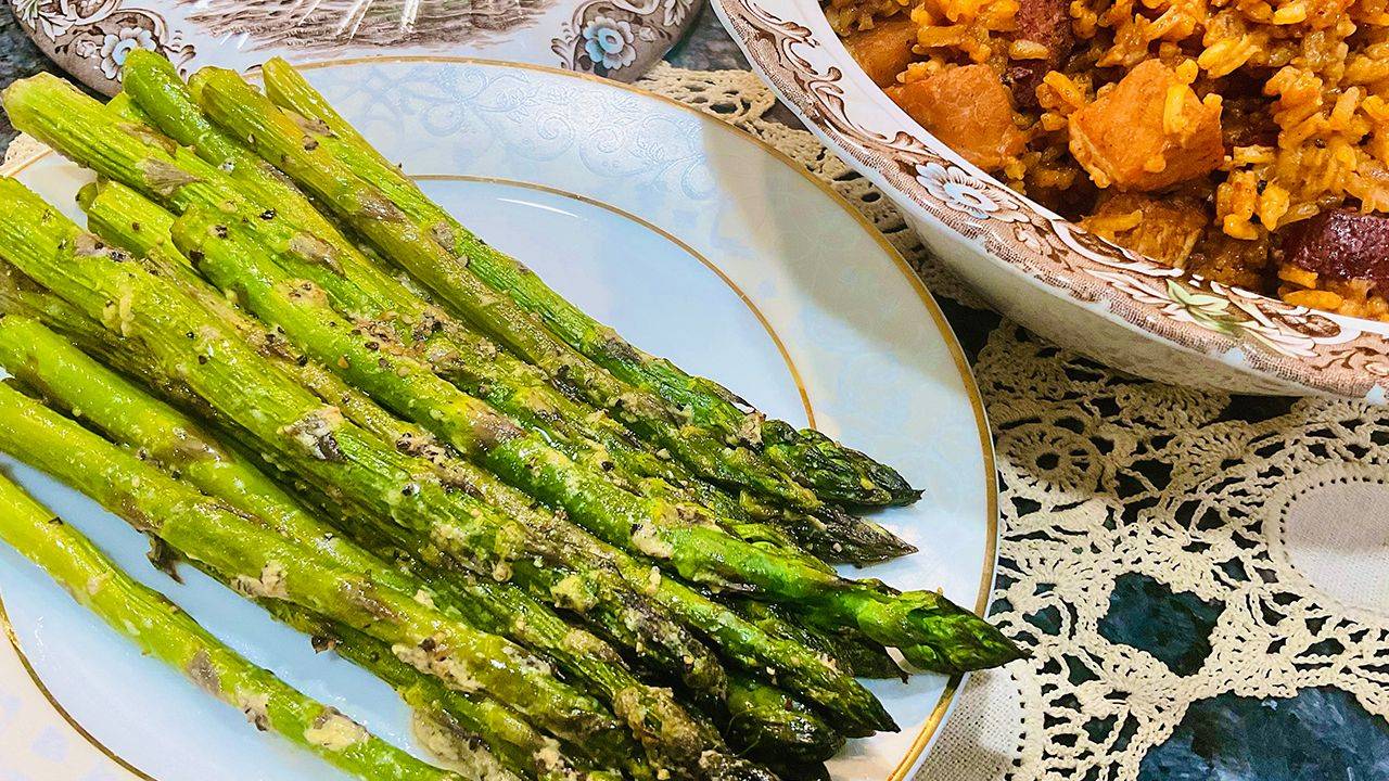 Roasted asparagus with honey mustard and lemon olive oil on a baking sheet.