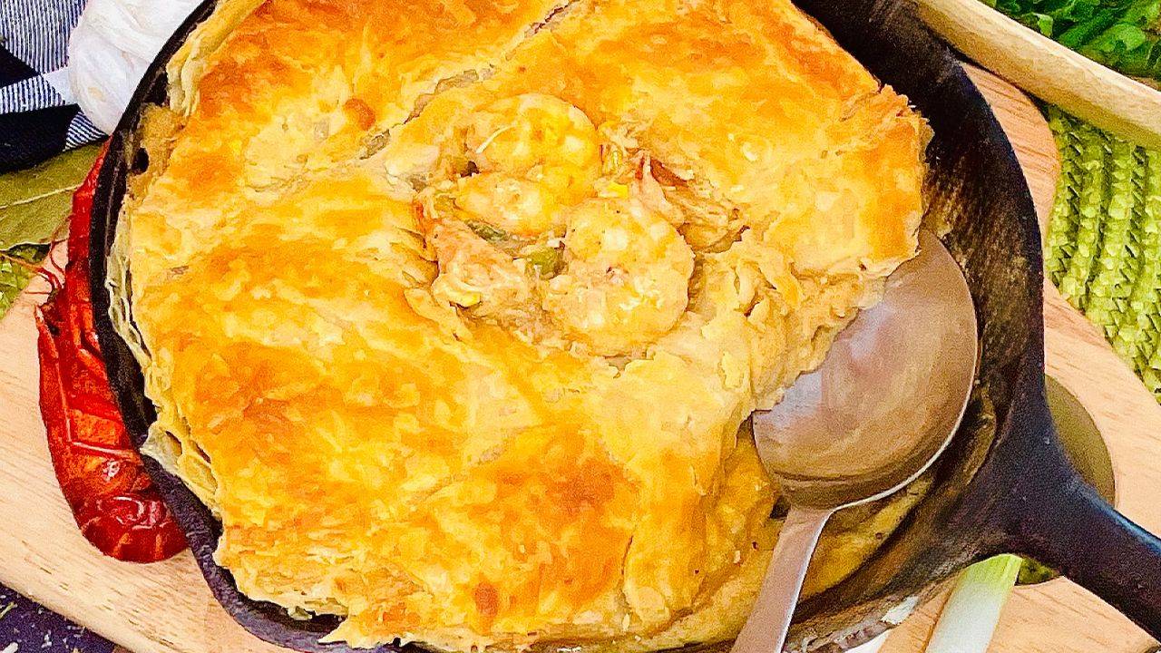 Cajun seafood cobbler with puff pastry topping baked until golden.