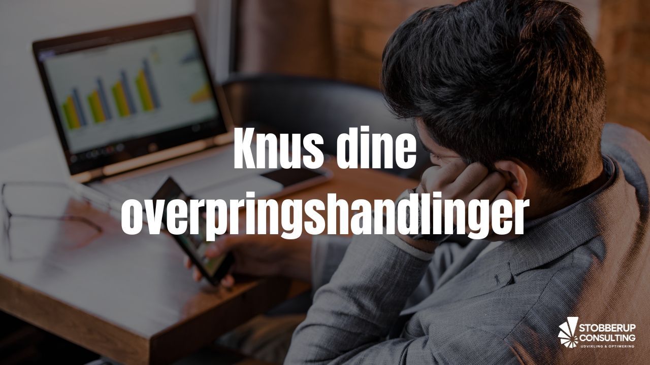 Mand distraheret af telefonen i stedet for at arbejde – symbol på overspringshandlinger.