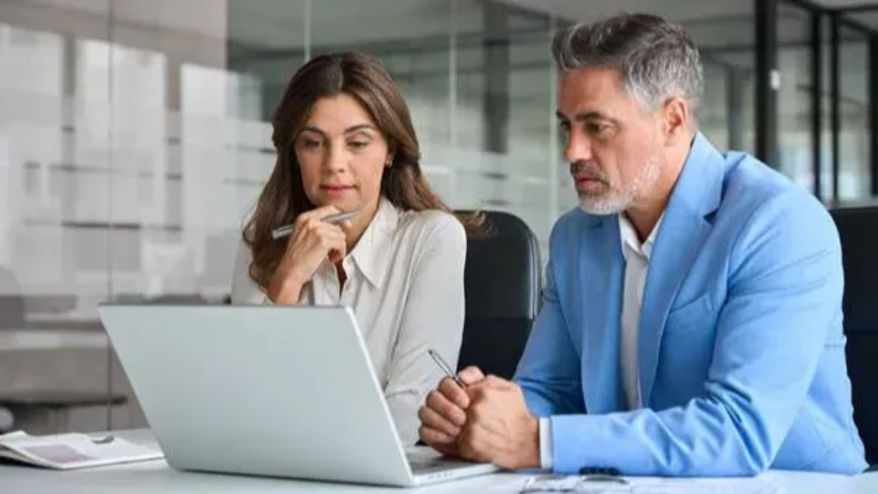 Business team of two busy professionals using laptop thinking on financial investment 
